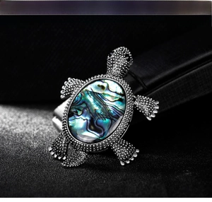 Detailed macro shot of vintage turtle brooch with colorful abalone shell on black leather