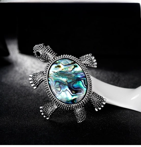 Detailed view of silver turtle brooch featuring a vibrant abalone shell inlay on dark texture