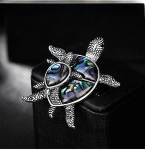 Macro detail of mother and baby turtle brooch with vibrant abalone shell inlay