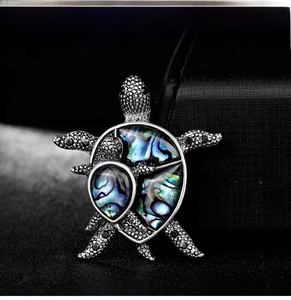 Detailed view of turtle brooch featuring natural abalone shell and silver textured scales