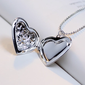 Silver heart floating locket necklace with rose relief on white book pages