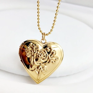 Macro shot of gold heart floating locket necklace with embossed rose and bead chain