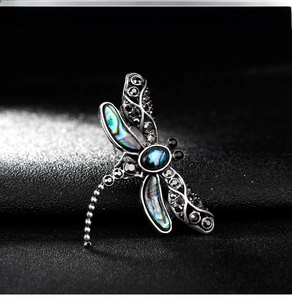 Macro view of dragonfly brooch with abalone shell wings and black gemstones detail