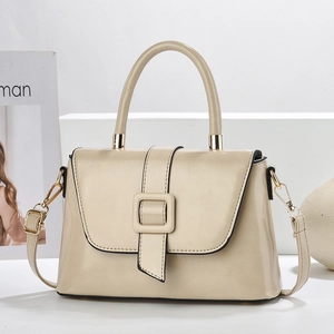 Détail de la texture cuir beige d'un sac élégant avec boucle carrée et bandoulière réglable