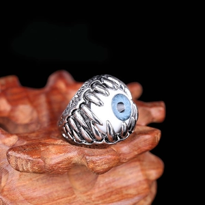 Macro shot of a vintage silver punk claw ring featuring a detailed blue evil eye centerpiece