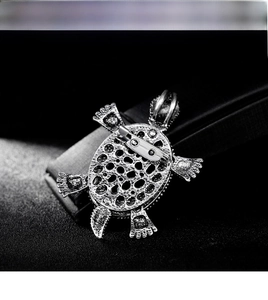 Detailed view of silver turtle brooch with intricate hollow metal textures and pin closure