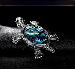 Macro shot of silver turtle brooch featuring colorful iridescent abalone shell inlay