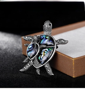 Macro shot of vintage silver turtle brooch featuring colorful abalone shell inlay details