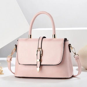 Pink lychee textured crossbody bag with gold hardware on white geometric pedestals
