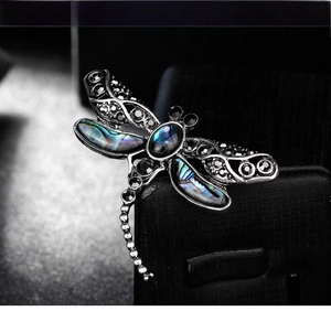 Macro view of dragonfly brooch with iridescent shell wings and dark rhinestones