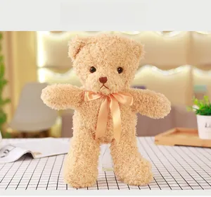 Close-up of light brown teddy bear with curly plush fur and golden silk ribbon bow