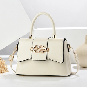 Detail van de elegante ivoren leren tas met gouden knoopsluiting en verfijnde afwerking