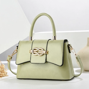 Lichtgroene gestructureerde handtas met gouden knoopsluiting op wit minimalistisch decor