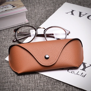 Tortoiseshell round eyeglasses with brown leather storage pouch on linen background