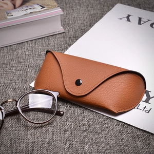 Brown lychee leather sunglasses case with vintage round frames on a desk setting