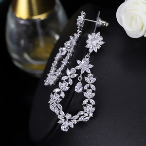 Macro shot of sparkling AAA cubic zirconia teardrop flower dangle earrings on a stand