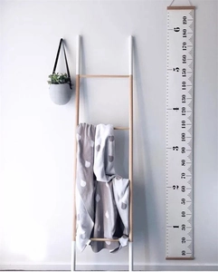 Detail of wooden height growth chart with CM and FT scales in a Nordic style room