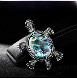 Macro shot of silver turtle brooch featuring iridescent blue-green abalone shell inlay