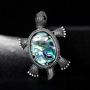 Vintage silver turtle brooch with iridescent abalone shell inlay on black background