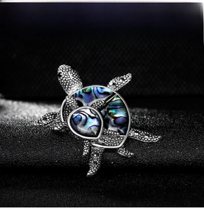 Macro shot of sea turtle brooch with iridescent abalone shell and silver textured alloy