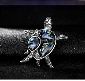 Detailed macro view of turtle brooch with shimmering mother-of-pearl inlay and silver texture