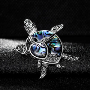 Elegant silver turtle brooch with rainbow abalone shell inlay on dark background