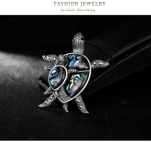 Macro shot of mother and child turtle brooch with iridescent abalone shell inlay
