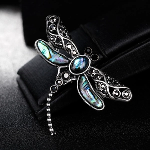 Silver dragonfly brooch featuring iridescent shell wings and dark gemstone accents