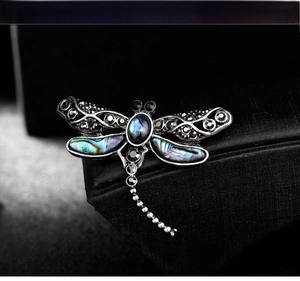 Detailed view of dragonfly brooch featuring colorful abalone shell and vintage metal