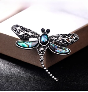 Macro view of dragonfly brooch with abalone shell inlay and black rhinestones on wings