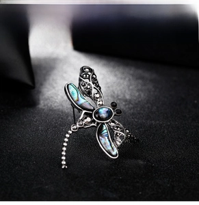 Macro shot of dragonfly brooch with iridescent abalone shell wings and silver metal