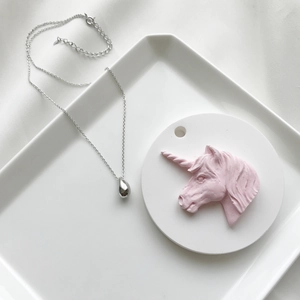 Detailed view of S925 sterling silver teardrop pendant necklace on a decorative white tray