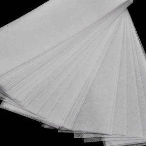 Stack of 100 white non-woven disposable hair removal wax strips on a black background