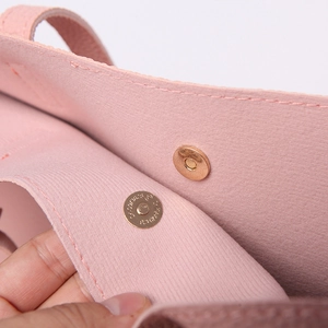 Detail of the golden magnetic clasp on a pink lychee grain leather handbag interior