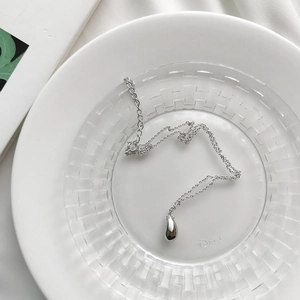 Macro view of minimalist silver teardrop pendant with fine adjustable link chain