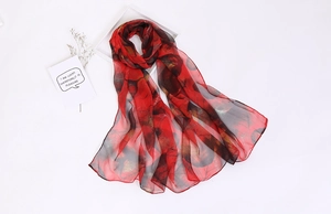 Detail showing red and black sheer georgette scarf with golden leaf patterns on white surface