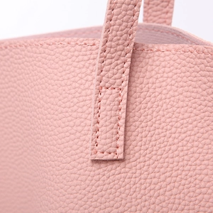 Close-up of pink lychee grain leather stitching and handle detail on a tote bag