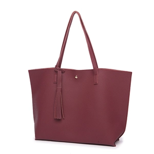 Detail view of burgundy lychee textured leather tote bag with tassel and magnetic buckle