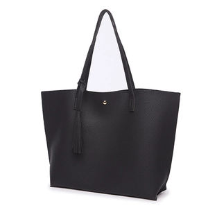 Detail view of black lychee-grain PU leather tote bag with tassel and gold stud closure