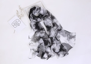 Detailed view of lightweight leaf pattern scarf in black and white sheer fabric