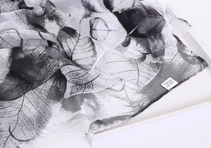 Macro detail of leaf pattern scarf with a label showing 100 percent silk feeling polyester