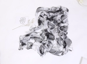 Detail of lightweight chiffon scarf featuring black and white leaf patterns on white background