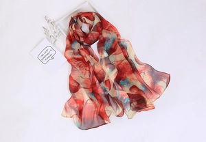 Lightweight sheer scarf with red and teal leaf patterns next to a white frame