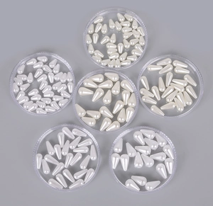 Detailed view of cream white teardrop ABS imitation pearls in clear containers for DIY