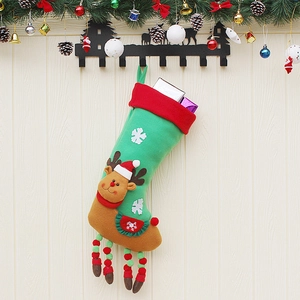 Green and red Christmas stocking with reindeer design hanging on a festive wooden wall