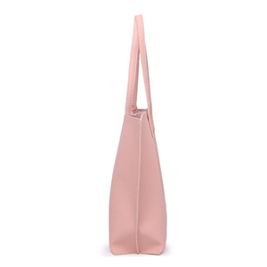 Side view detail of pink tassel tote bag showing litchi texture and handle structure
