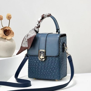 Detail van blauwe geweven lederen crossbodytas met decoratieve zijden sjaal