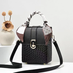 Detail van zwarte lederen crossbody tas met geweven textuur en decoratieve zijden sjaal