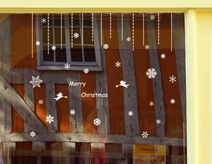 Detail view of white Christmas snowflake decals and Merry Christmas text on a glass window