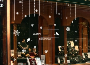 Detail of white snowflake window clings with Merry Christmas text on a glass store front
